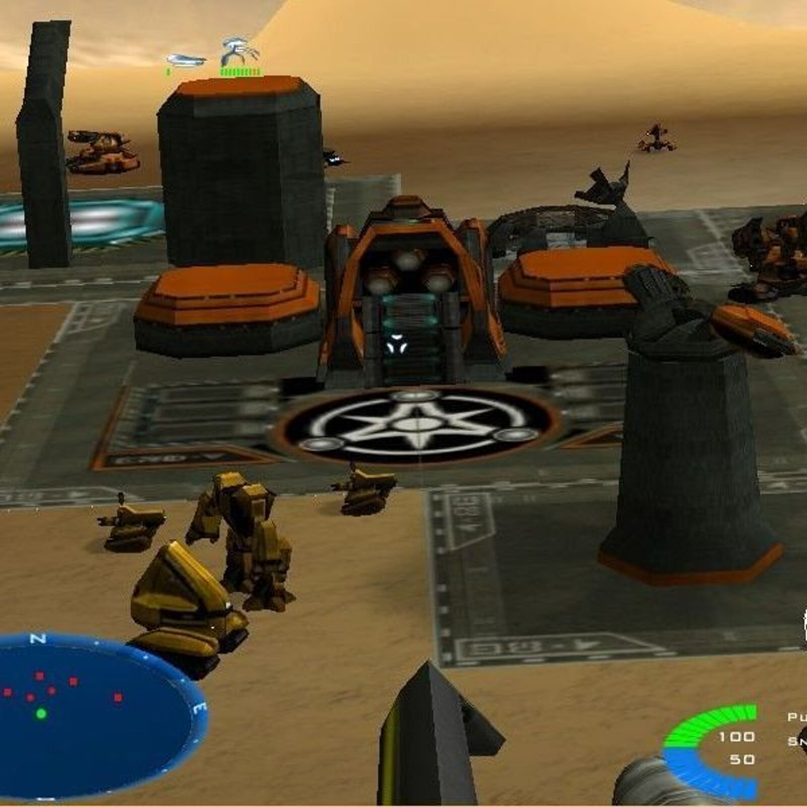 In a futuristic desert landscape of Battlezone II: Combat Commander, advanced structures, vehicles, and machinery surround a central building with orange and gray details. Enhanced graphics highlight radar and HUD elements on screen, evoking the tactical feel of a real-time strategy game.